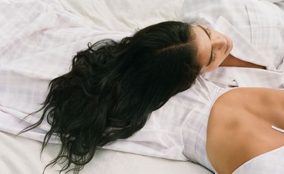 woman with long black hair lying against woman in white dress