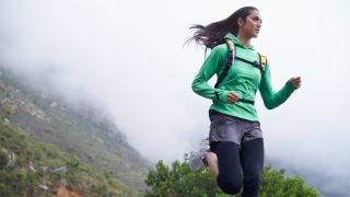 Woman running in mountains wearing backpack