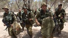 Israeli soldiers walk to their deployment area on the border with Gaza