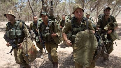 Israeli soldiers walk to their deployment area on the border with Gaza