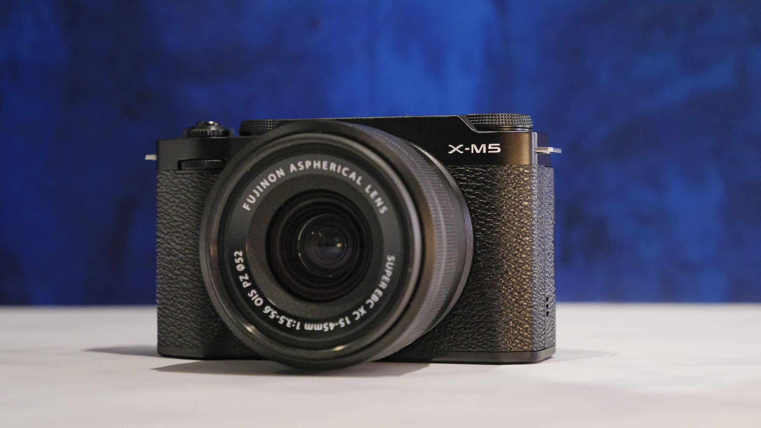 Fujifilm X-M5 camera on a marble surface with rich blue background