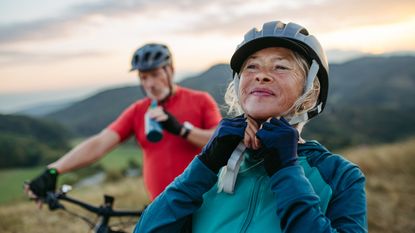 A retired couple go biking in a park.