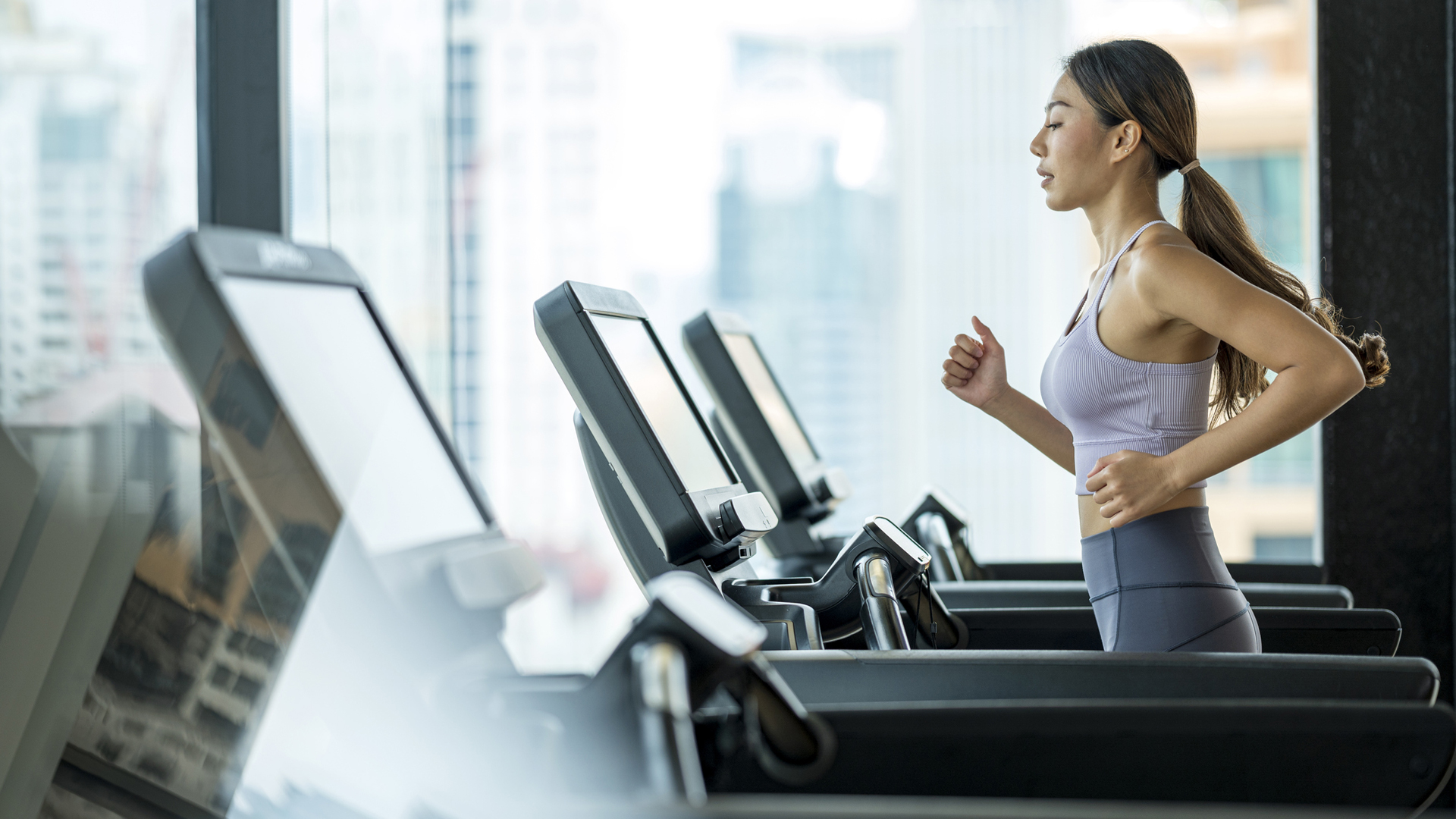 خمسة أفكار للمرح Cardio HIIT Workouts: امرأة تركض على جهاز الجري في صالة الألعاب الرياضية