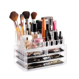 A multi-tiered acrylic makeup organizer with makeup in it