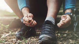 A hiker tying their shoelaces