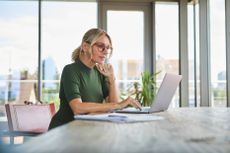 A business woman is working on her laptop at a dining table.