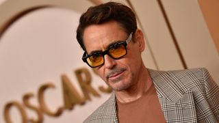 US actor and Oppenheimer star Robert Downey Jr., wearing a stylish houndstooth jacket and yellow-tinted glasses, attends the Oscars 2024 