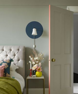 Bedroom with painted door trim, round painted detail around wall light, bedside table, bed