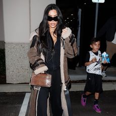 Kim Kardashian wearing a floor-length fur coat with an all-black outfit 