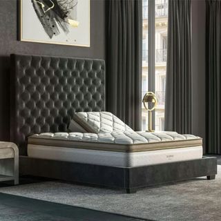 Saatva Solaire Mattress on a gray bed base against a gray wall.