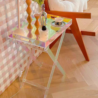 An iridescent folding side table in a neutral warm and pink living room