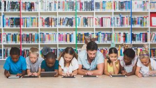 Man reads with kids on floor of library 