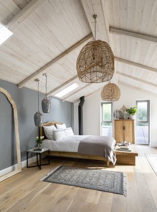 attic bedroom with wooden panelled roof, wooden flooring and blue walls