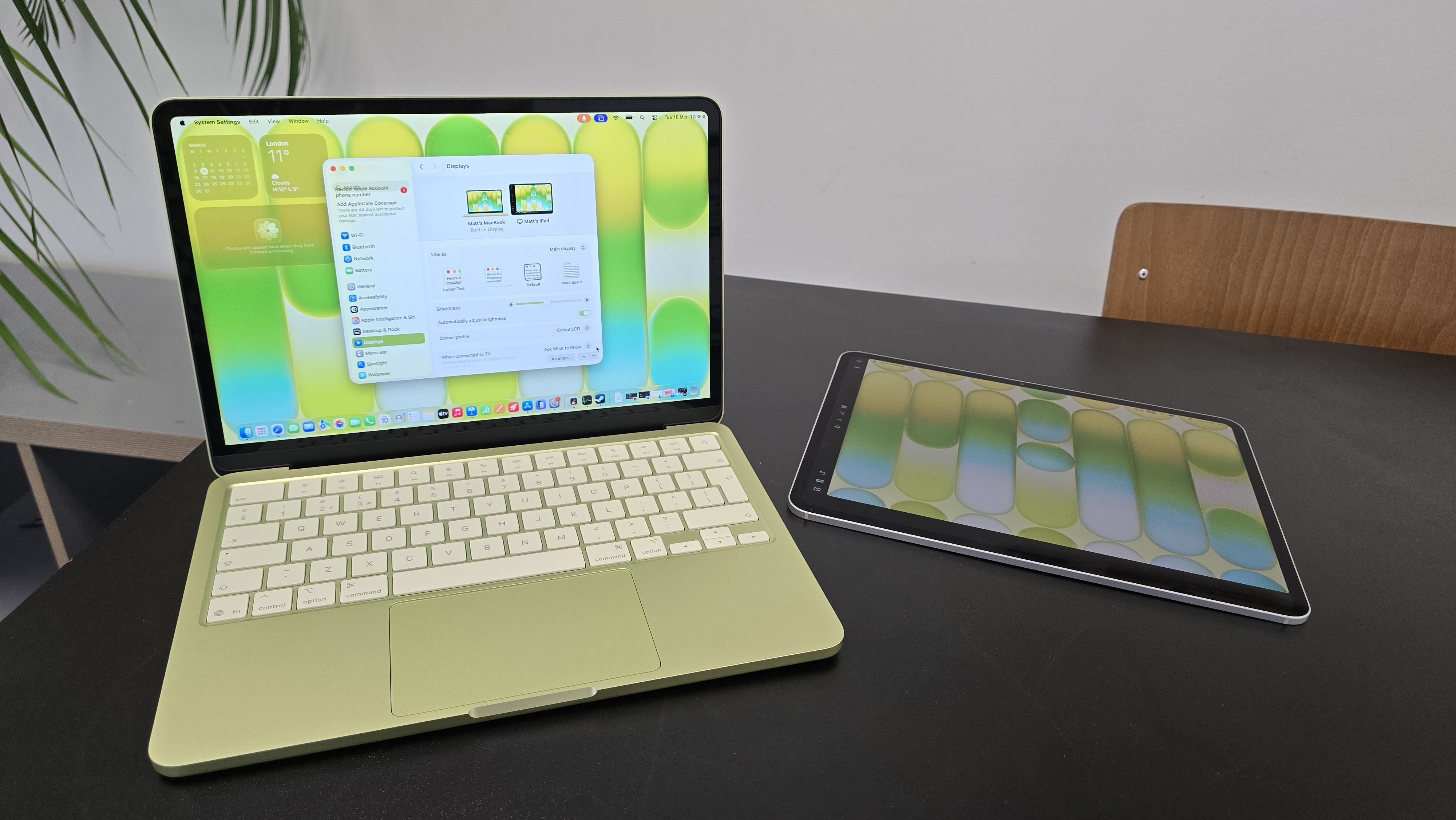 MacBook Neo laptop on a desk with plant in background