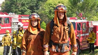 Bode Donovan and a female firefighter covered in ash look upset at something off camera.