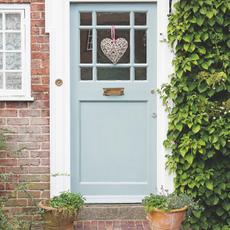 Blue door on red brick property with ivy wall on right hand side