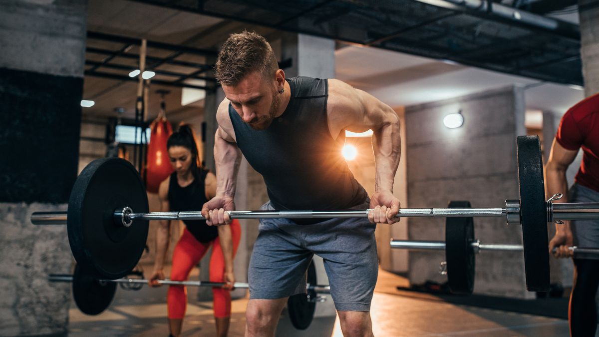 Three people in the gym performing the reverse-grip bent-over row exercise with barbells