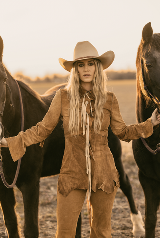 lainey wilson wears a suede ensemble and poses with two horses in a whirlwind promotional shot