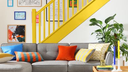 Grey L Shaped Sofa with colorful cushions with yellow staircase paint idea in background