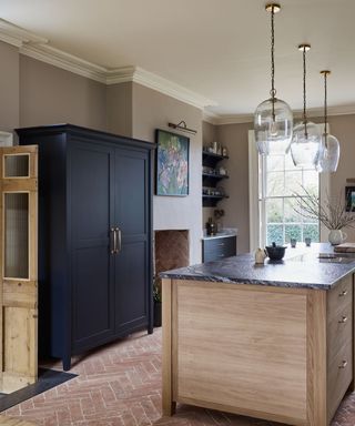 small kitchen with large pantry cupboard and terracotta floor
