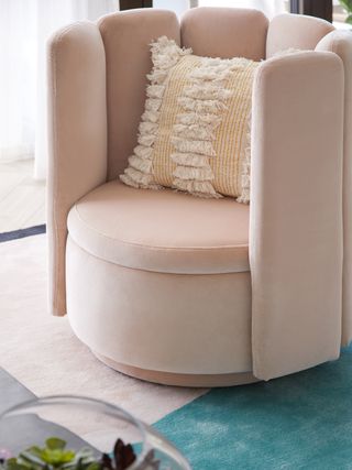 Curved armchair in warm neutral with pillow