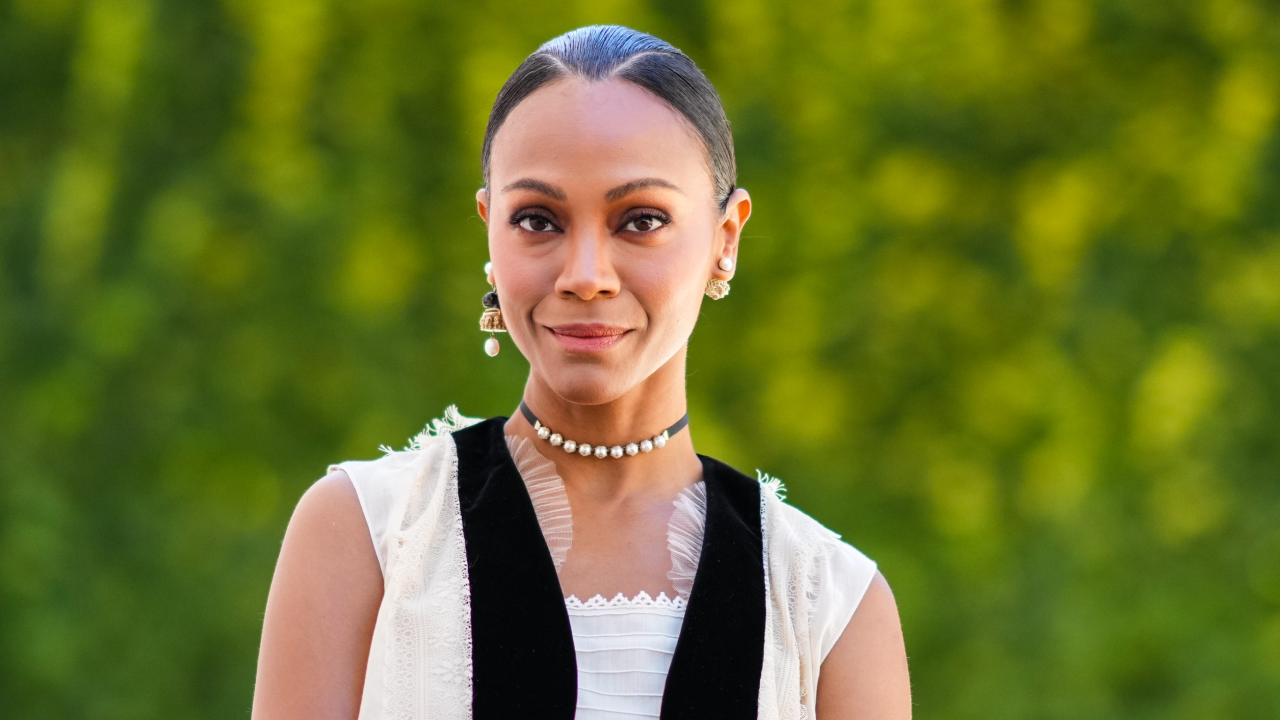 Zoe Saldaña in a bun with a white shirt and black scarf