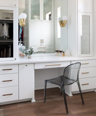 Styled vanity area in neutral bedroom with built in closets surrounding a large mirror