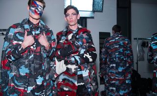 Male models in blue, grey, white and red camo outfits and camo face paint