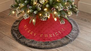 A red Christmas tree skirt with a fluffy gray rim.