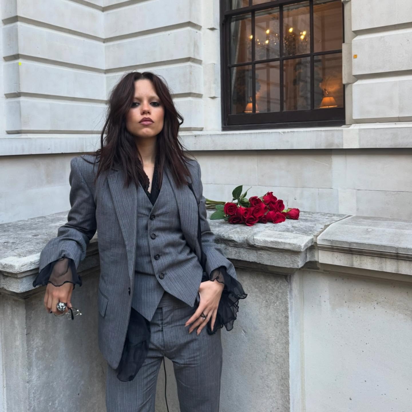 Jenna Ortega wearing a grey suit with a muted shag haircut