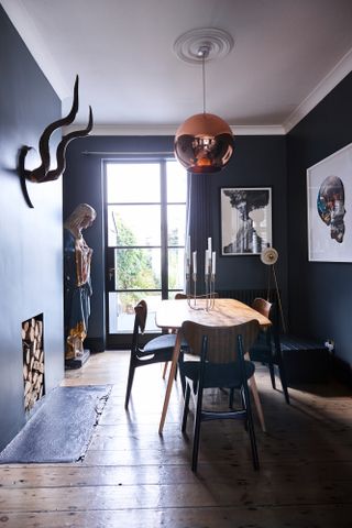 Jason Traves house: Sophisticated dining room with dark grey walls, wooden floorboards, mid-century style light oak dining table and copper pendant ceiling light