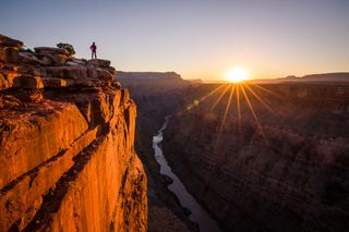 A woman looking at Grand Canyon and Colorado River from Toroweap Overlook at sunrise, North Rim, Grand Canyon National Park, AZ