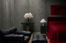 A bedroom with dark gray walls and dark red bedding