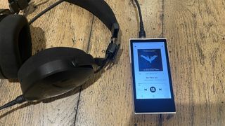 Activo P1 hi-res music player on wooden surface next to headphones