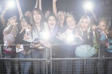 Crowd of young female fans screaming and cheering at concert