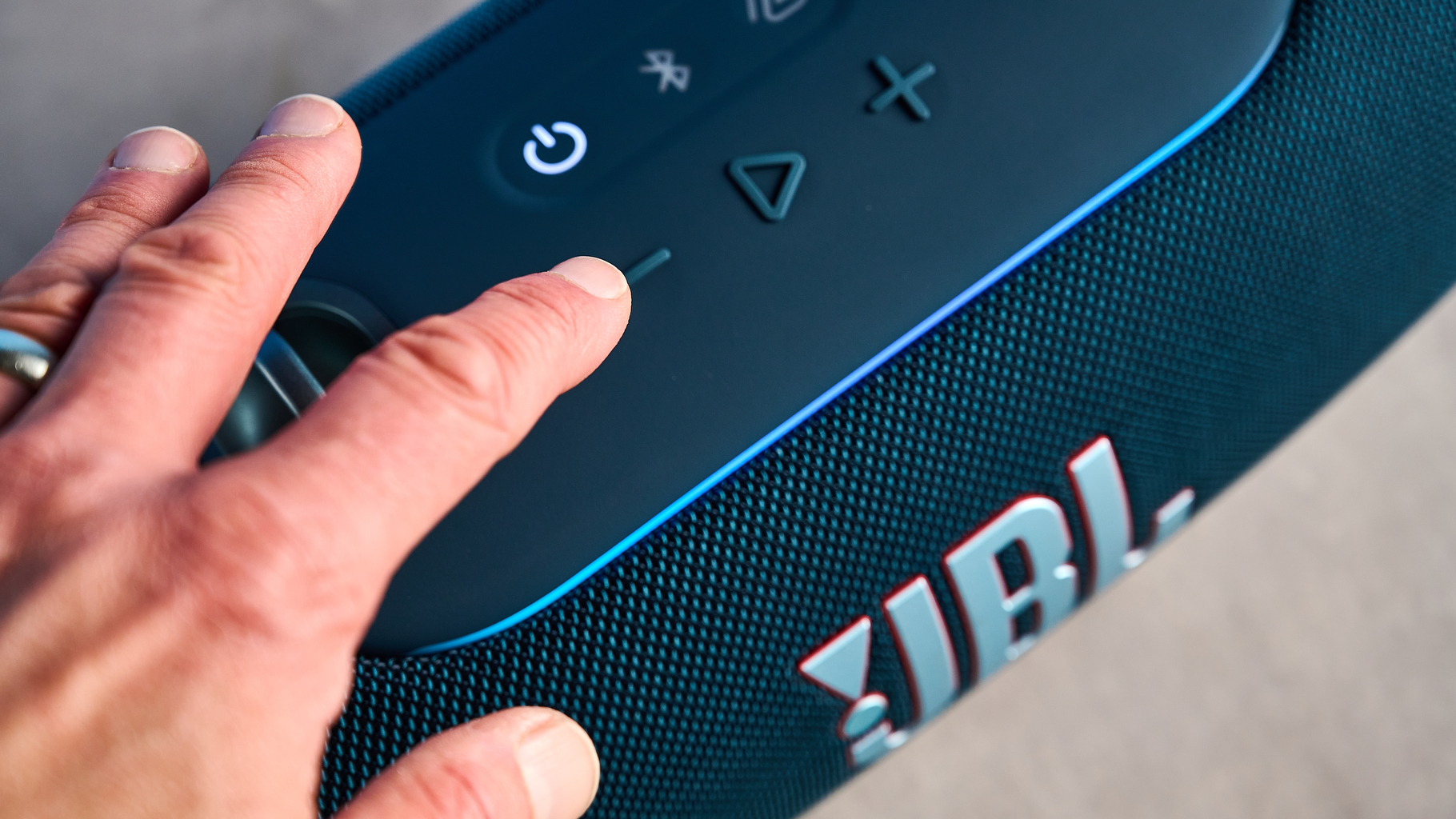 the JBL Xtreme 5 bluetooth speaker in blue shown with the rugged carry strap and buttons