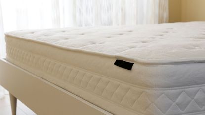 A bare white mattress in a white room