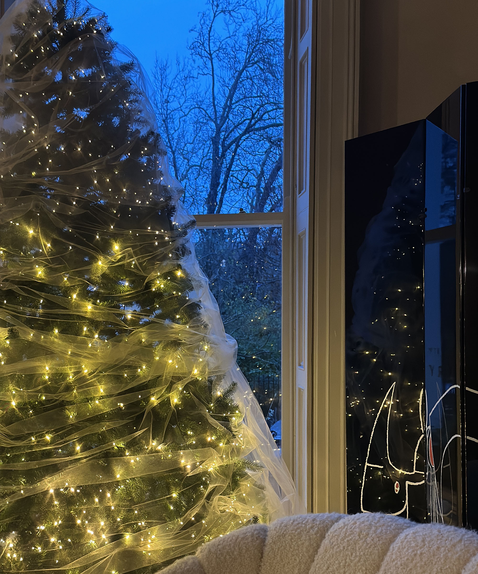 veiled tree lit up in front a window at nighttime