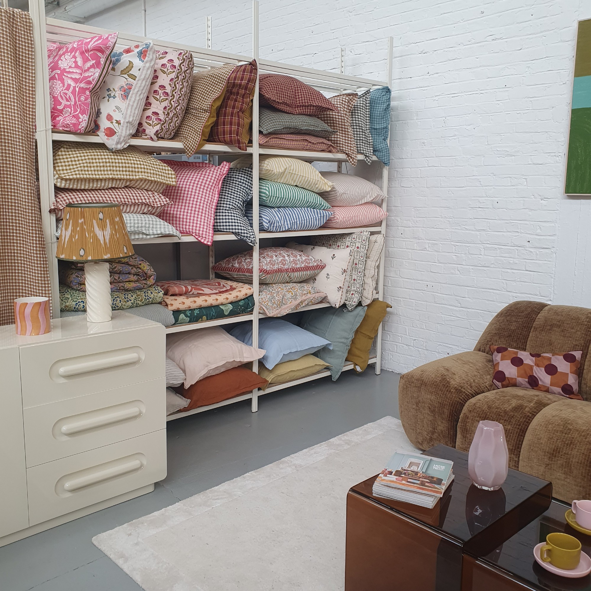 La Redoute HQ wish shelves filled with pillows dressed in the new collection bed linen with a lacquered sideboard and the corduroy Nuria sofa next to it