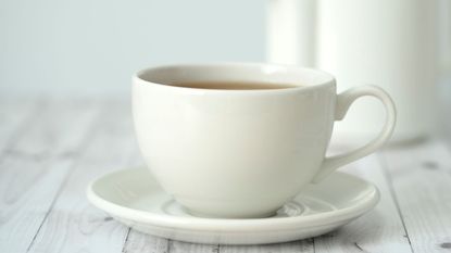 Best teacup and saucer set: a cream teacup and saucer on a wooden surface
