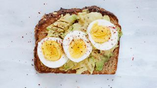 Slice of toast with two boiled eggs, avocado and butter, an example of what to eat after a workout