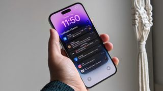 En hand håller upp en iPhone 14 Pro Max med Notification Center uppe på skärmen.