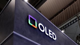 A sign at a trade-show with OLED in bold white letters with a colorful square next to it.