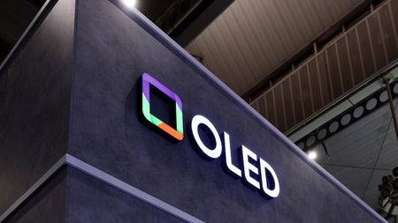 A sign at a trade-show with OLED in bold white letters with a colorful square next to it.