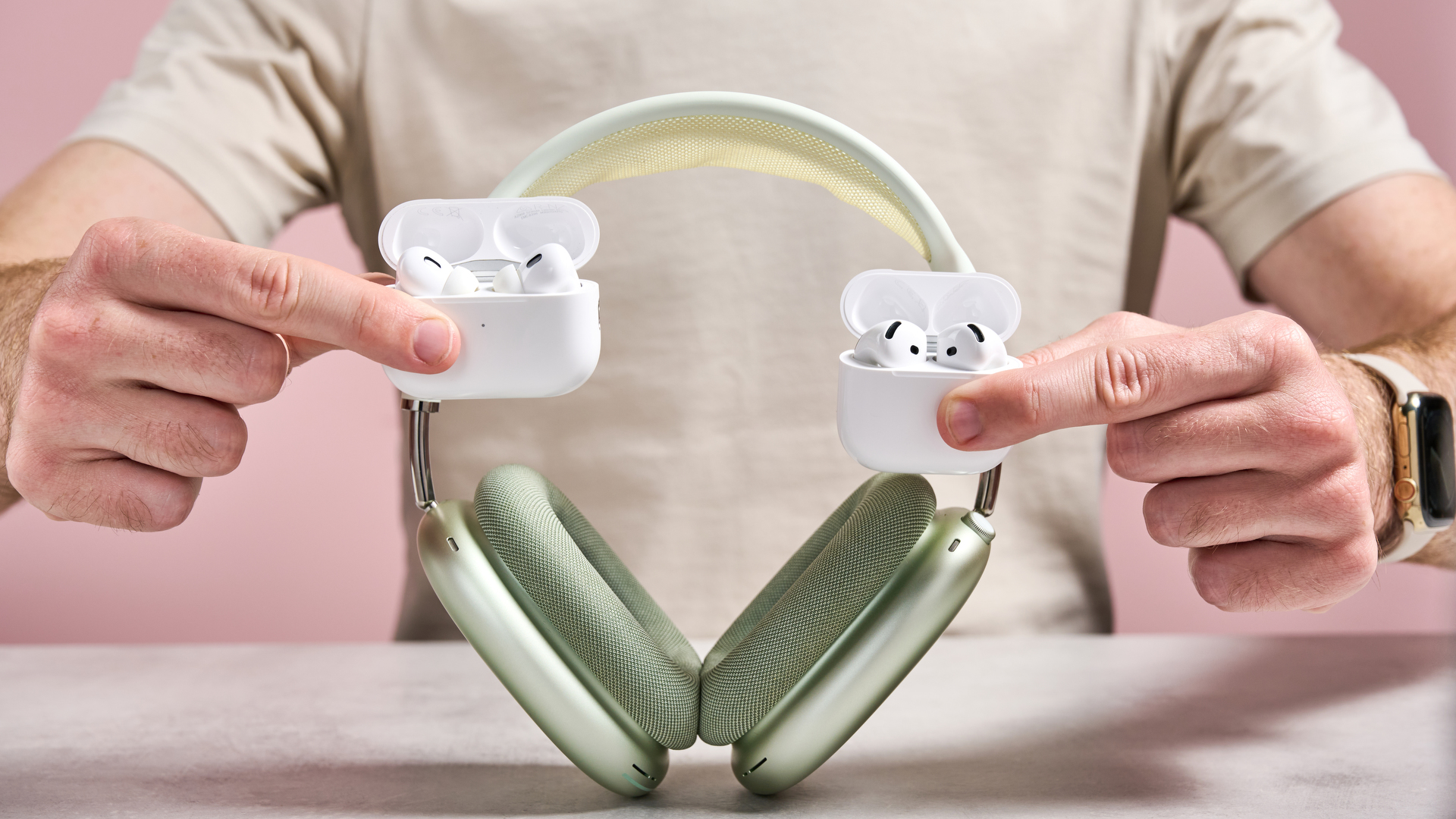 AirPods Pro 2, AirPods 4 and AirPods Max being held together in front of a man's torso
