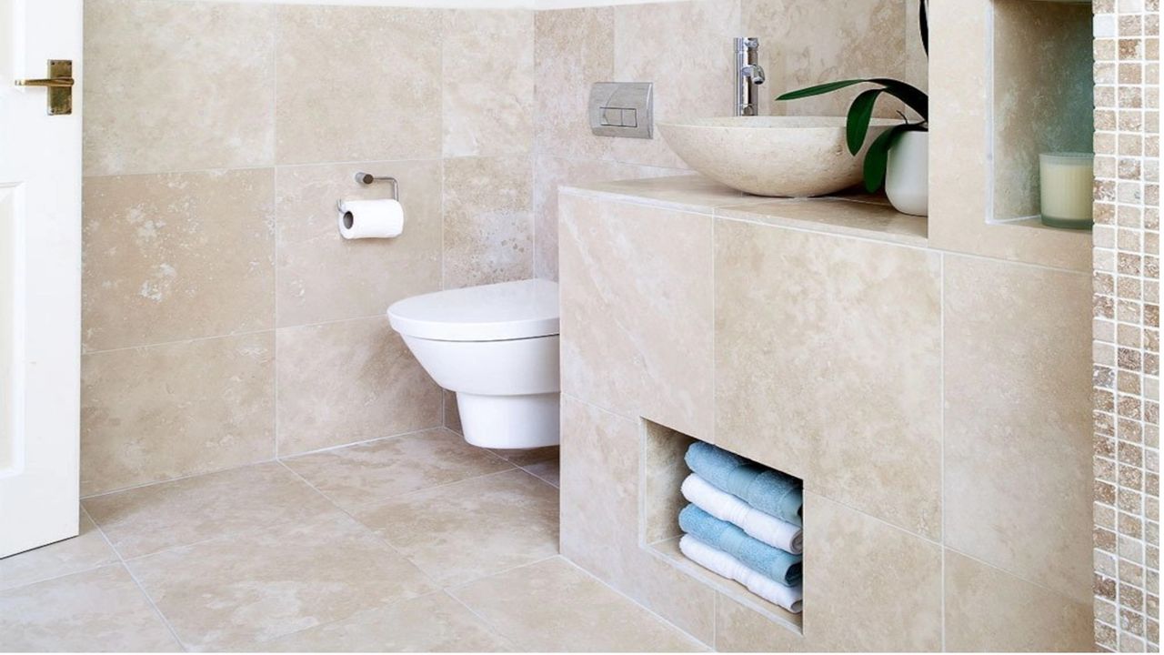 cloakroom with beige wall tiles with alcove storage and white toilet