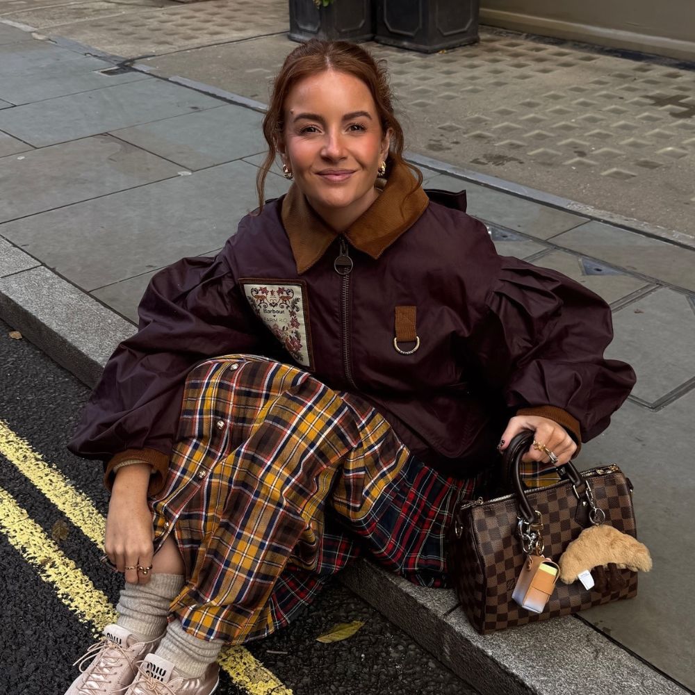 Influencer @rebeccaferrazwyatt wears Miu Miu satin elasticated trainers with a plaid skirt and burgundy jacket.