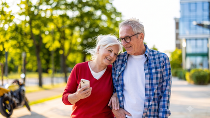 A happy older couple walks outside, leaning into eachother.
