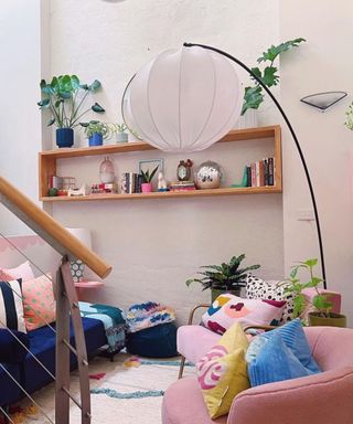 A staircase leading to a small living room with a couch, decorative shelf, and lighting