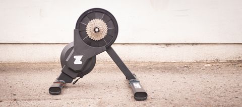 Zwift Hub trainer stands on a tarmac floor in front of a white wall